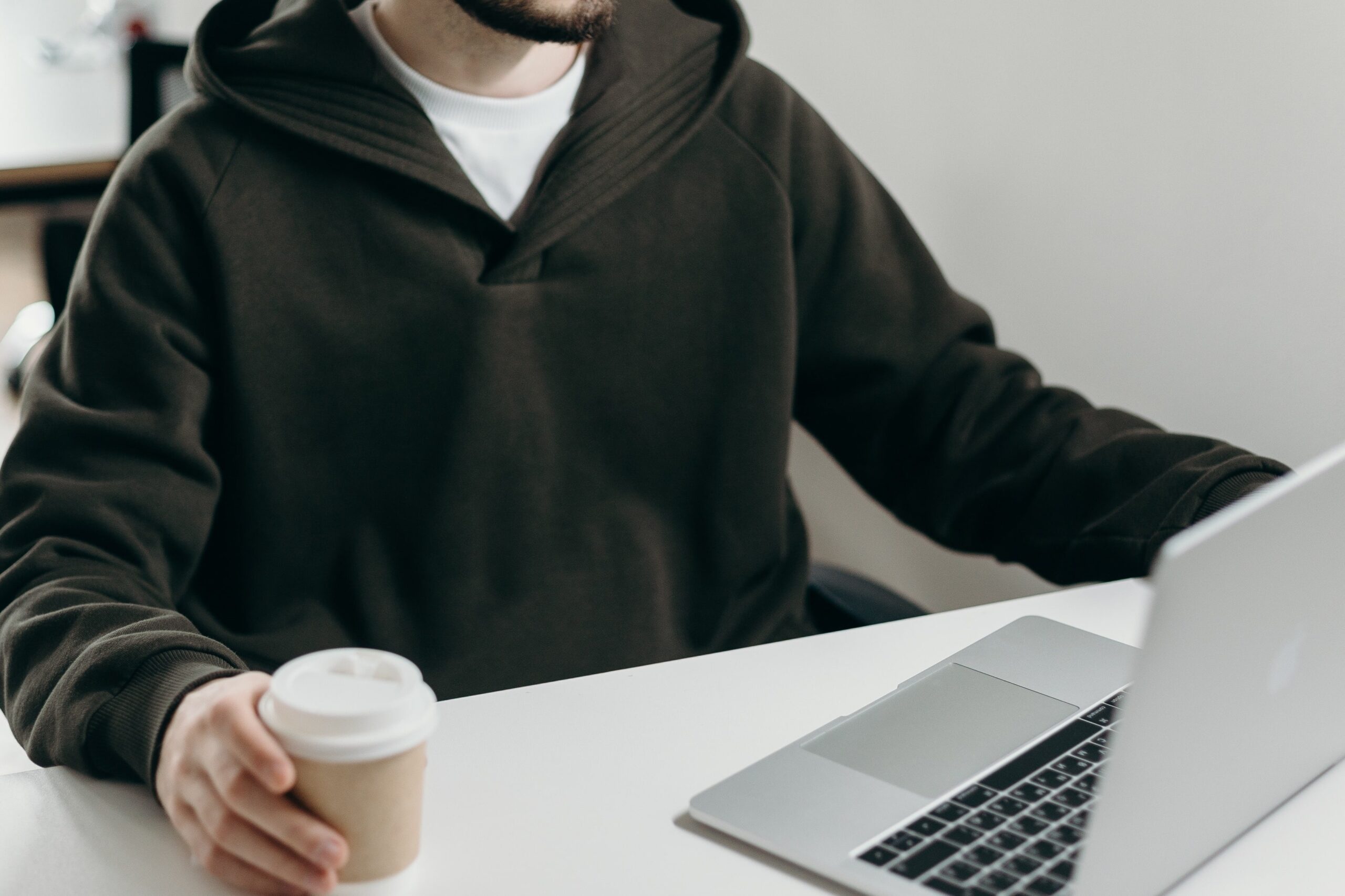 Mand sidder ved sin computer med en kaffekop i hånden