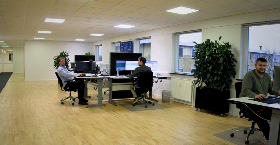 office-3-wide-sm Gældsrådgiver sidder ved sit skrivebord og i baggrunden er de øvrige rådgivere